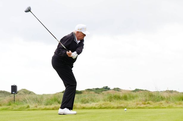 US President Donald Trump takes a shot from the first tee at the opening of the Trump International Golf Links
