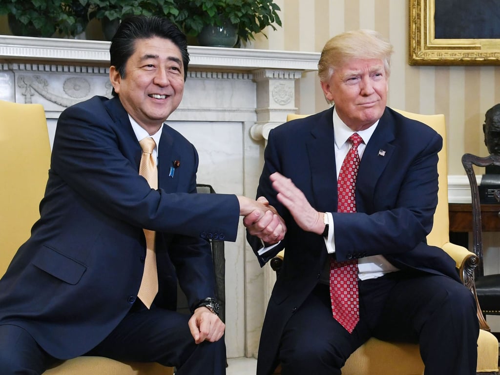 Japanese Prime Minister Shinzo Abe (left) shakes hands with Trump at the White House in February 2017. Photo: Kyodo