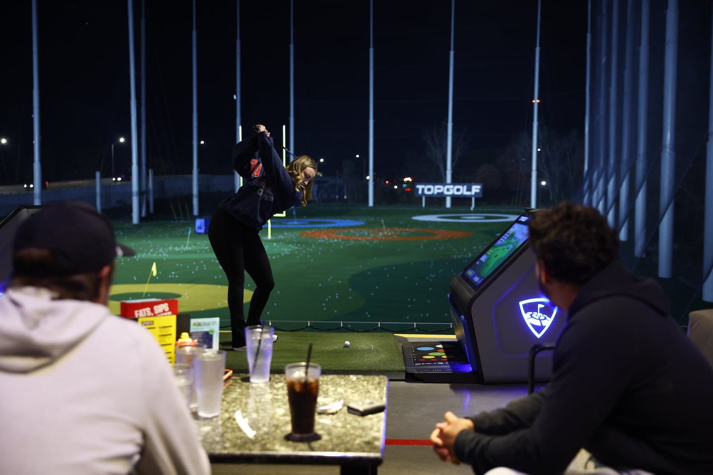 Bryce Barringer's wife, Bella, hits a shot during a recent outing at Topgolf.