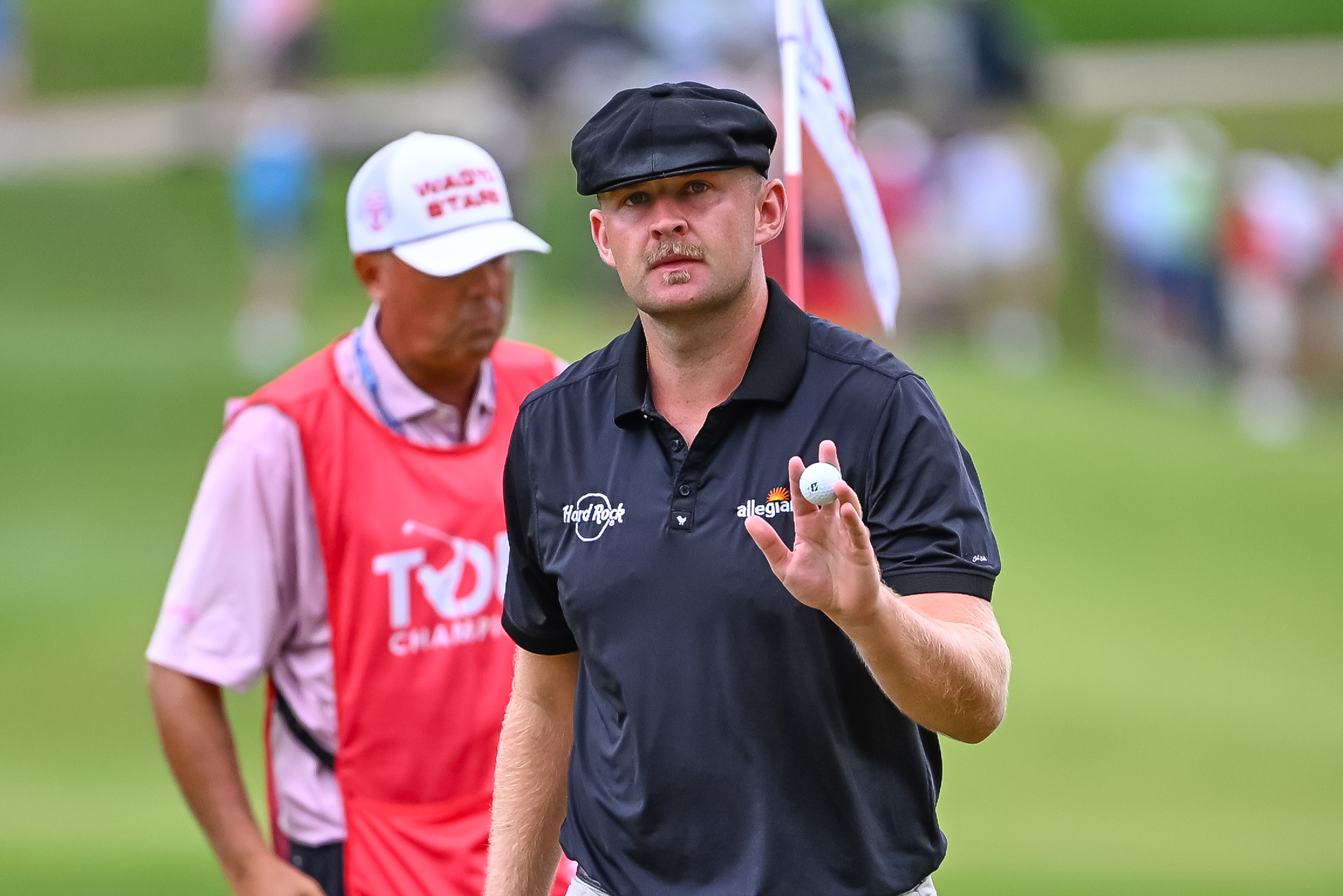 Harry Hall waves to the crowd after holing a putt
