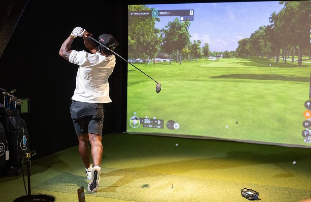 A person playing golf indoors on a simulator.
