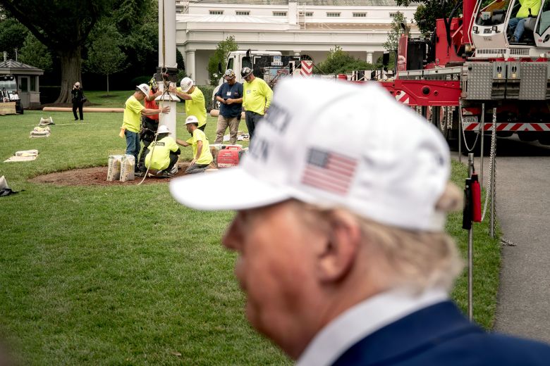 President Donald Trump speaks to members of the media as workers install a new flagpole on the South Lawn of the White House, on June 18.