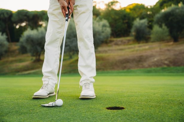 Closing putt on the green. A golfer is aiming for the hole. Close up shot.