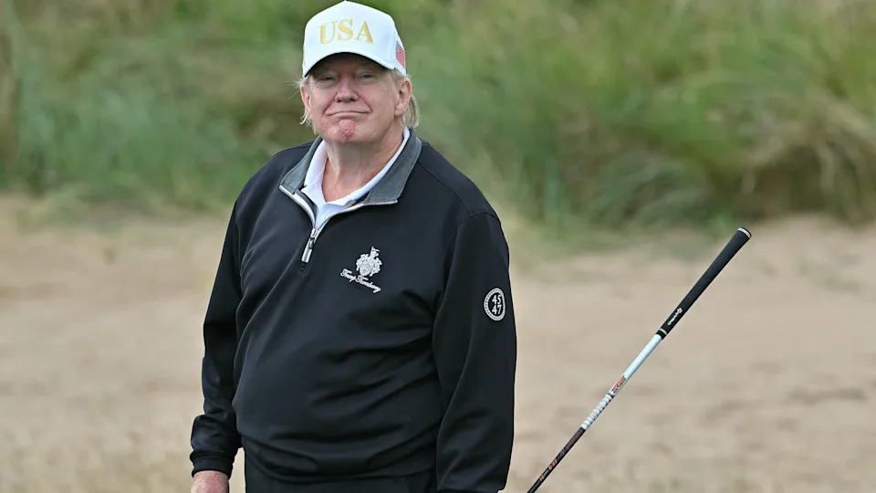 US President Donald Trump reacts after playing from the first tee to officially open the Trump International Golf Links course