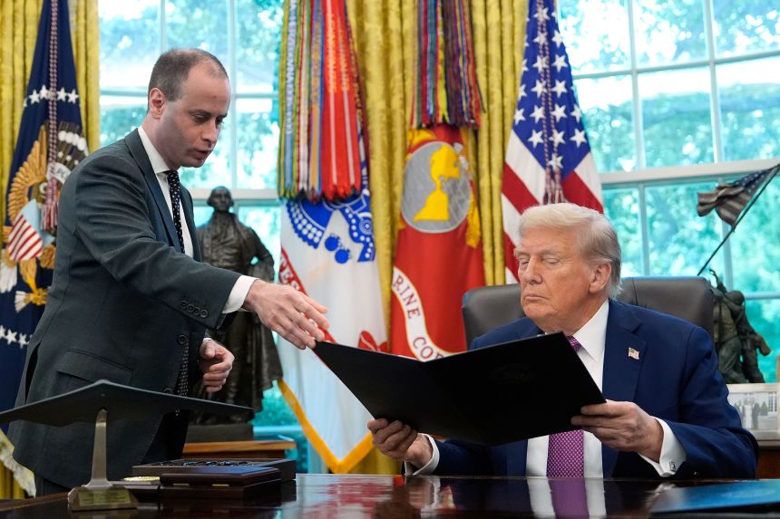 White House staff secretary Will Scharf hands President Donald Trump a something to sign in the Oval Office of the White House, on September 5.