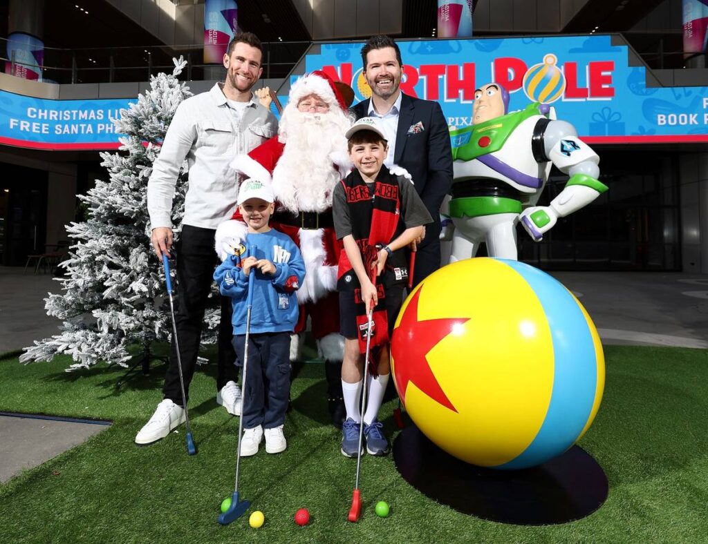 a family ready to play Pixar Putt at Marvel Stadium next to the iconic Pixar ball, as well as Santa and Buzz Lightyear