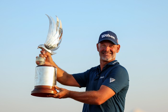 Paul Waring Paul Waring, in blue Nike shirt and cap, smiles as he holds the Abu Dhabi Golf Championship 2024 trophy.