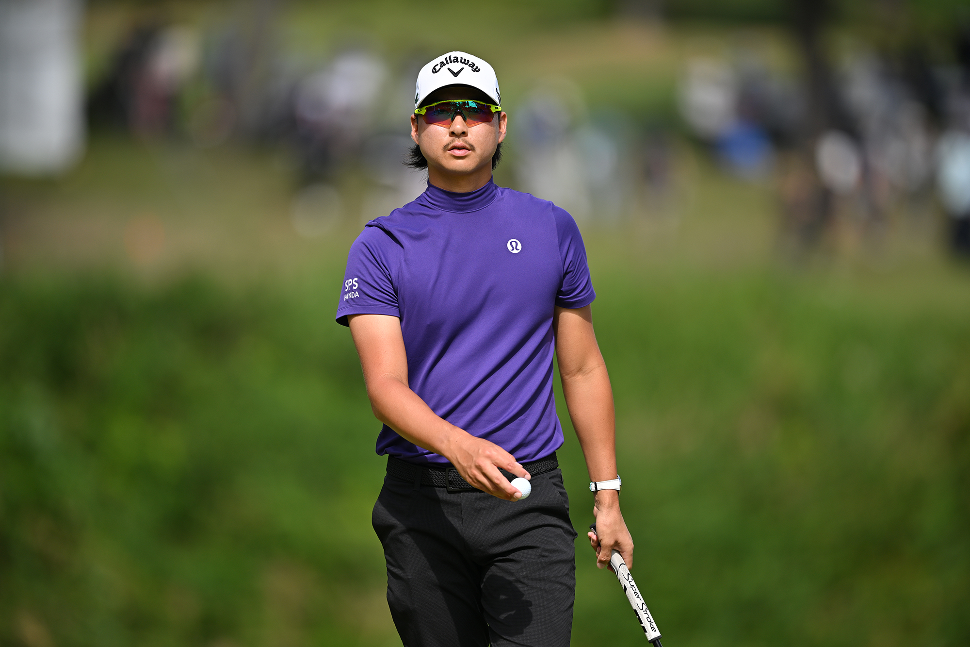 Min Woo Lee walking with his golf ball in his hand