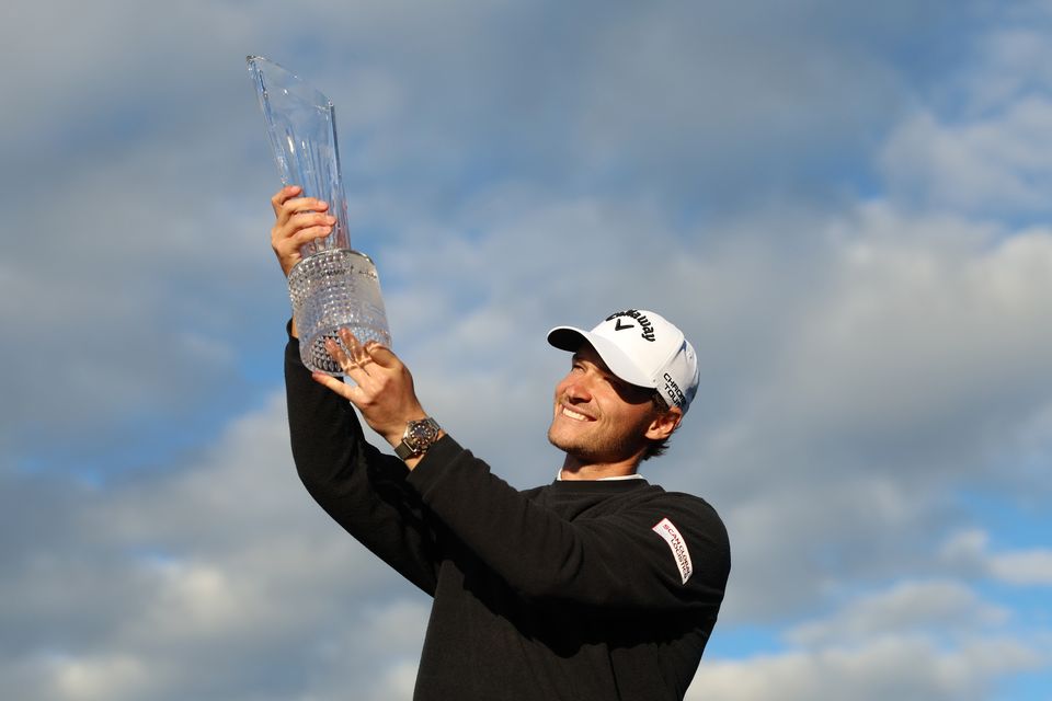 Rasmus Hojgaard of Denmark poses for a photo as he celebrates with the trophy on the 18th green after winning during day four of the Amgen Irish Open 2024 at Royal County Down