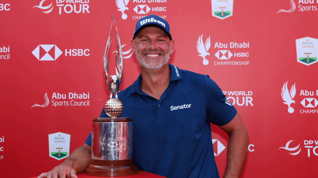 Paul Waring smiles while posing next to the Abu Dhabi HSBC Championship trophy