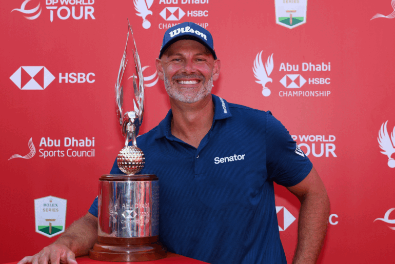 Paul Waring smiles while posing next to the Abu Dhabi HSBC Championship trophy