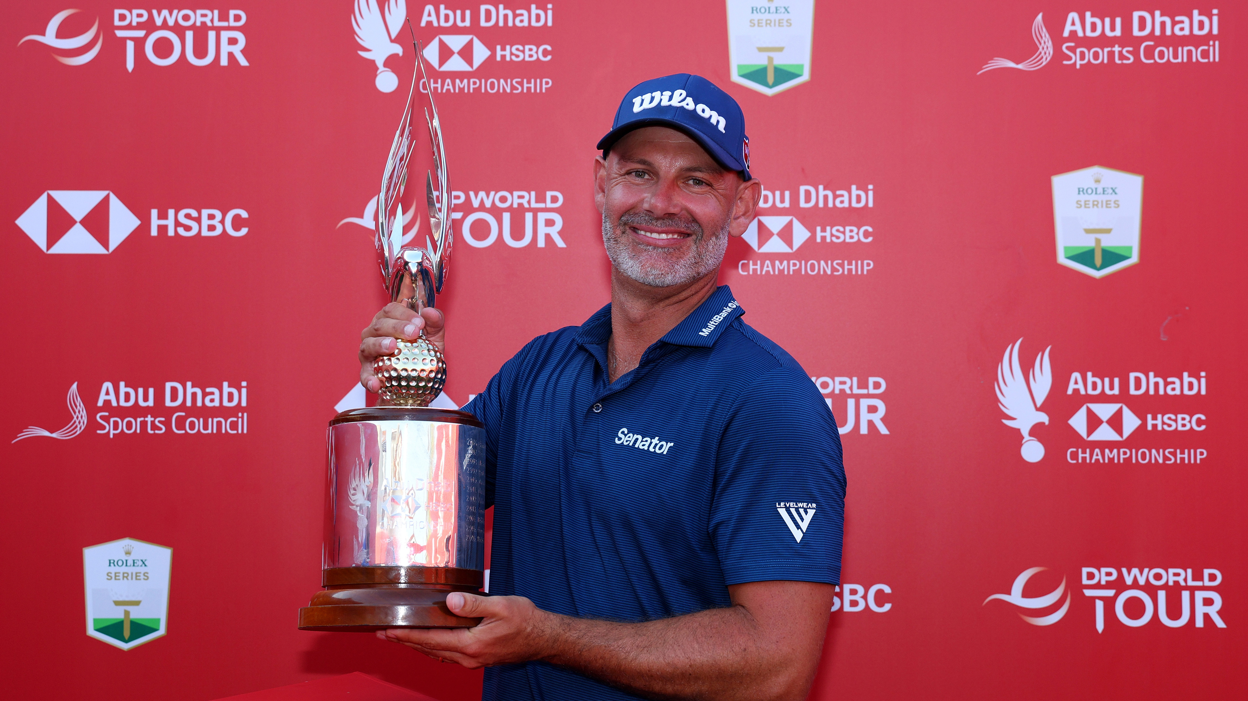 Paul Waring smiles as he poses with the 2024 Abu Dhabi HSBC Championship