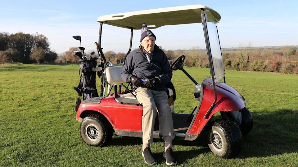 Archie is pictured sat on a red golf buggy with a bag of golf clubs on the back