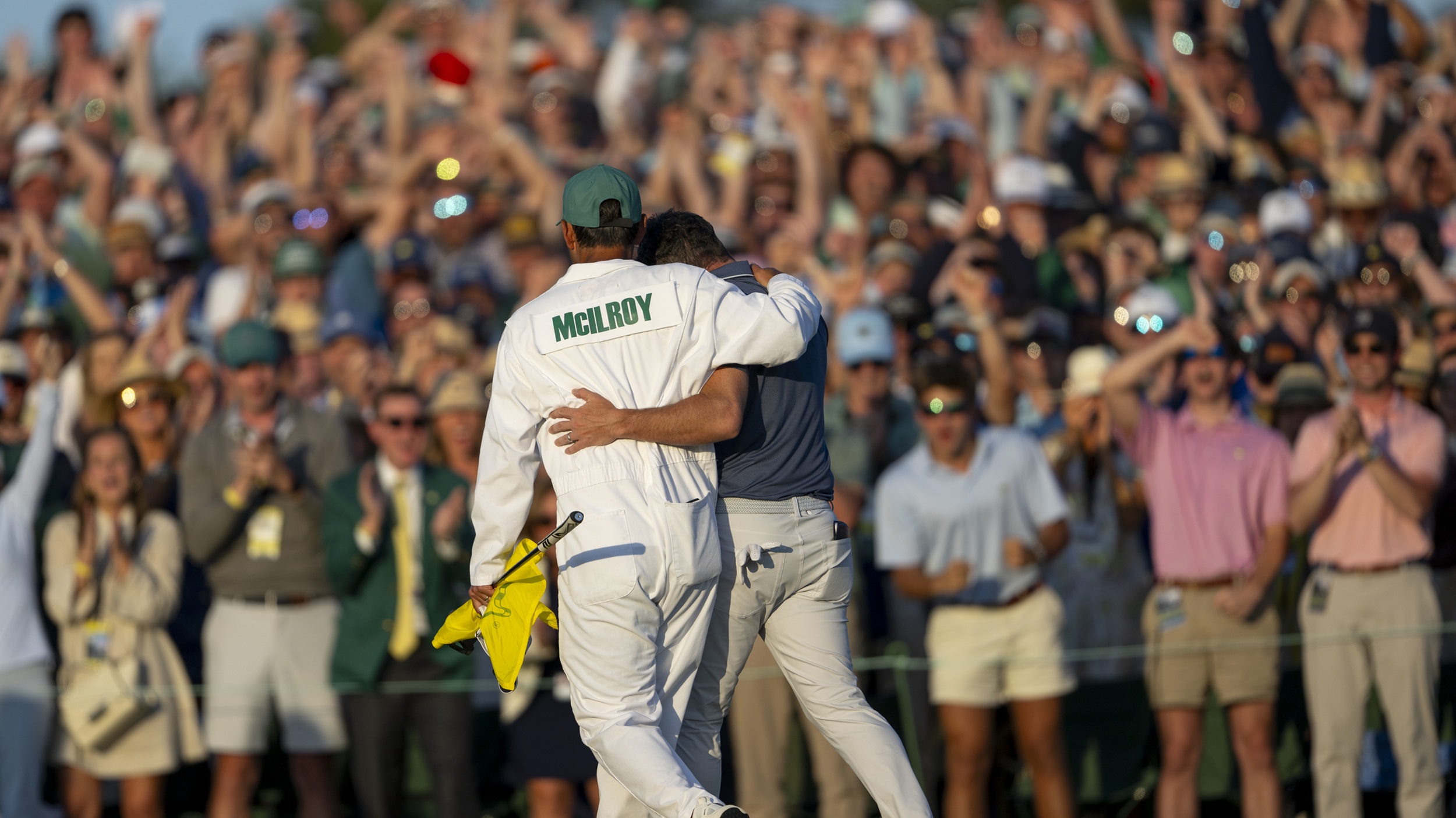 Rory McIlroy and his caddie Harry Diamond walk off the 18th green arm in arm after winning the 2025 Masters