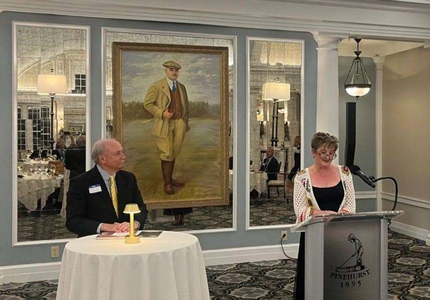 Pinehurst Mayor Pat Pizzella and Dornoch Provost Cath McAngus flanking a portrait of Donald Ross.