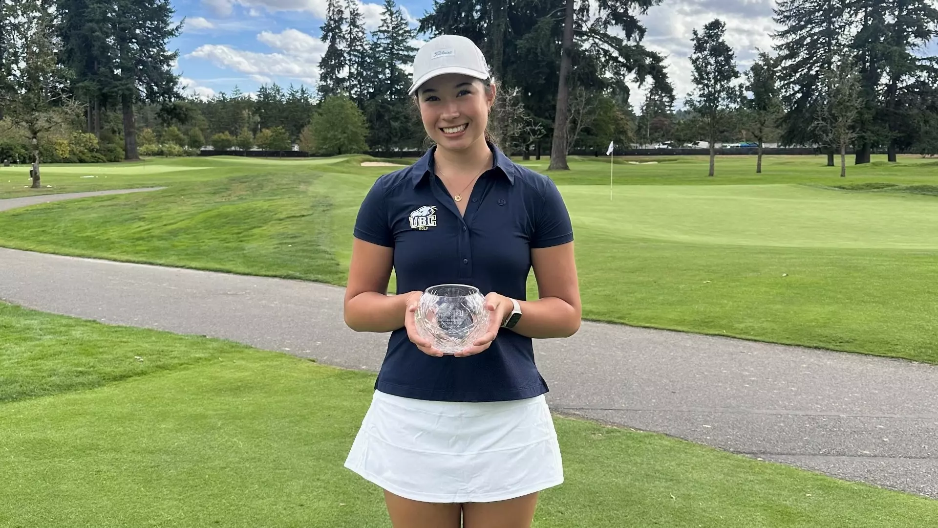 Sienna Harder smiling and posing with a round glass trophy after winning the individual championship at the Harbottle Invitational