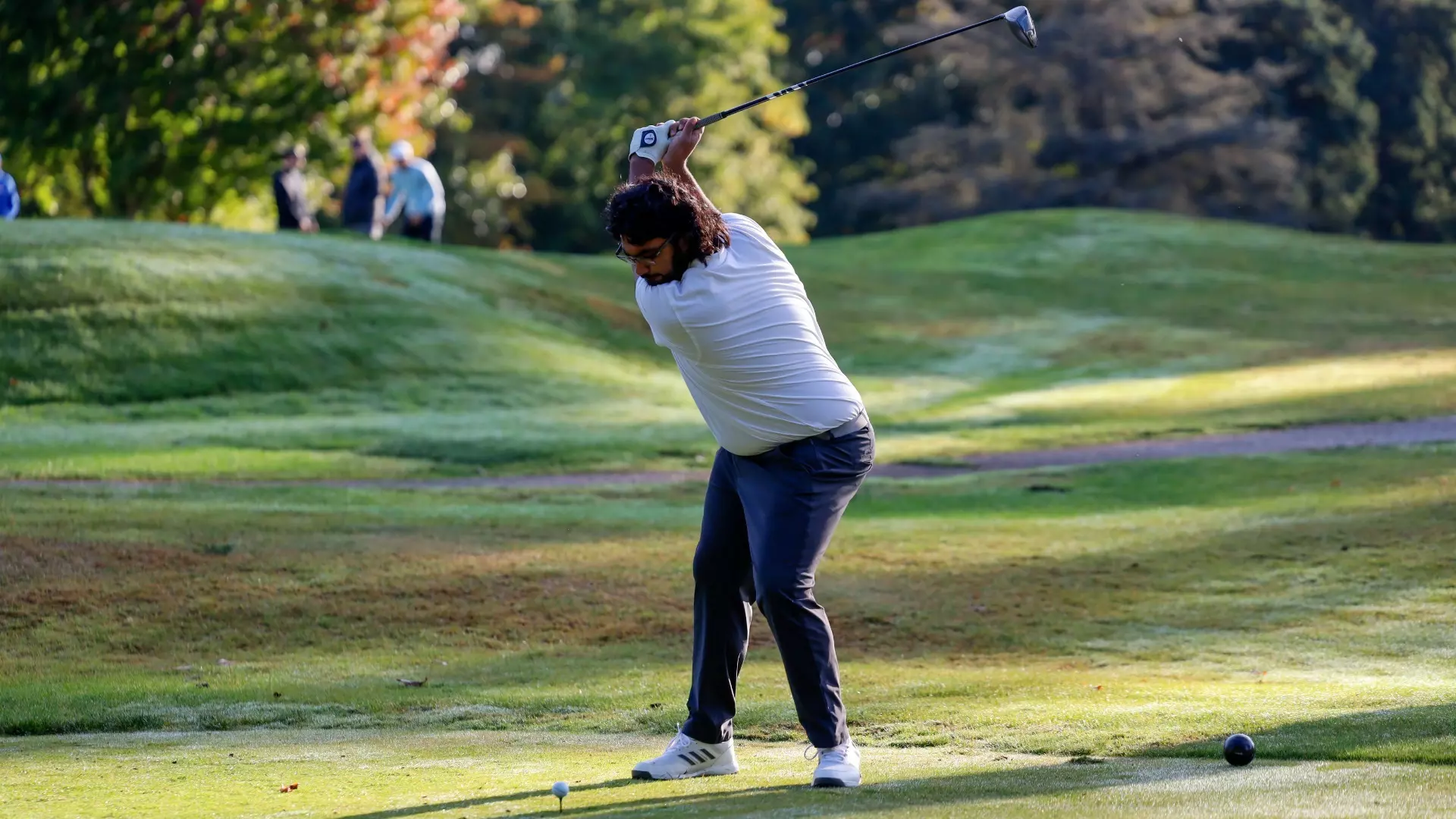 Manny Lalh at the peak of his backswing, about to hit a ball with his driver from a tee box
