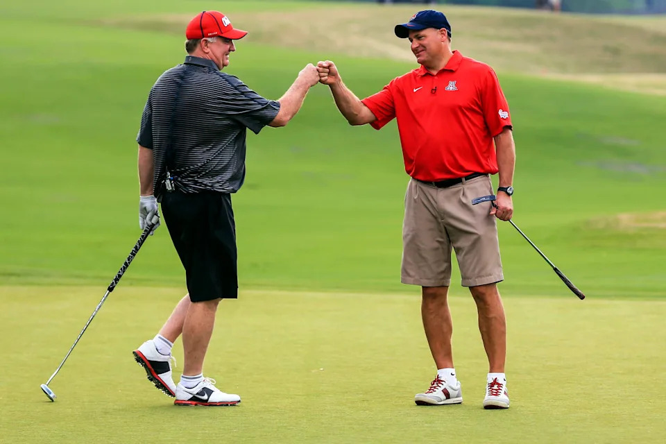 Apr 28, 2014; Greensboro, GA, USA; Mississippi Rebels head football coach Hugh Freeze (left) celebrates finishing play for the day with Arizona head football coach Rich Rodriguez at the Chick-fil-A Challenge at Reynolds Plantation Resort. Mandatory Credit: Daniel Shirey/CFA-pr via USA TODAY Sports **HAND OUT PHOTO **