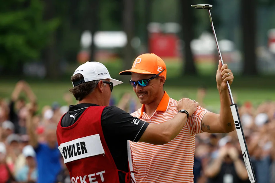 Rickie Fowler and his caddie, Ricky Romano, celebrate on the 18th green after defeating Adam Hadwin and Collin Morikawa in a playoff to win the Rocket Mortgage Classic at Detroit Golf Club on July 02, 2023 in Detroit, Michigan.