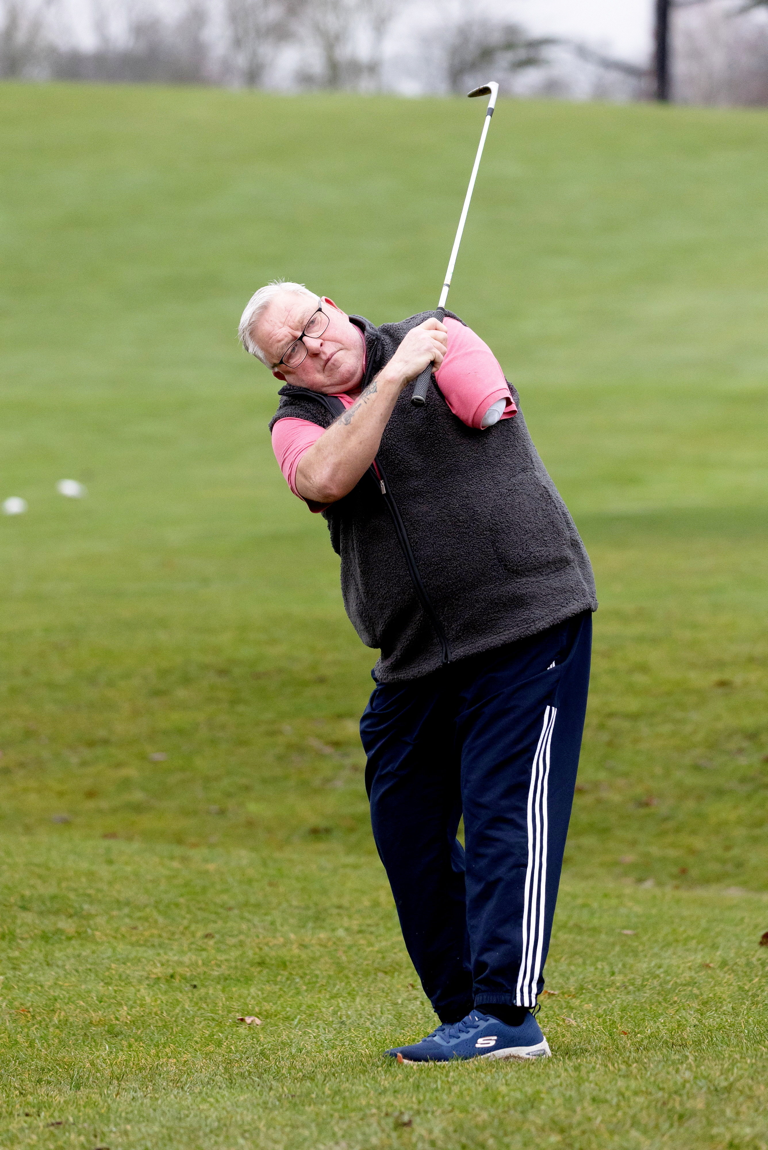 Patrick Duke, a disabled golfer with one arm, swings a golf club on a green course.