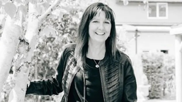A black and white photo of a woman in a black leather jacket smiling