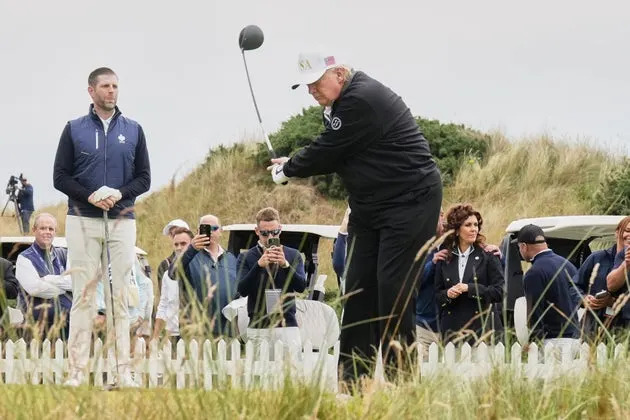 President Donald Trump tees off as Eric Trump (left) stands by during the opening ceremony for the Trump International Golf Links golf course, near Aberdeen, Scotland, in July.