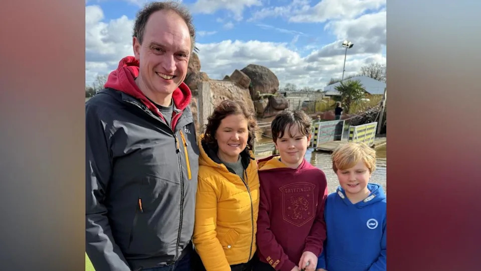 John O’Driscoll, Sarah O’Driscoll and their children Fin and Zac at Mr Mulligan's Dino Golf in Tonbridge, Kent. All four are holding golf clubs. John and Sarah are wearing puffer jackets, while Fin and Zac are wearing hoodies. The golf course can be seen in the background.