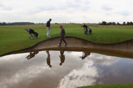 John Jacobs (L) of Cumberwell Park Golf Club looks for his ball in a flooded bunker with Richard Dinsdale of Parc Golf Academy during the Lombard Challenge Regional Qualifier at Cumberwell Park Golf Club on August 6, 2012 in Bath, England