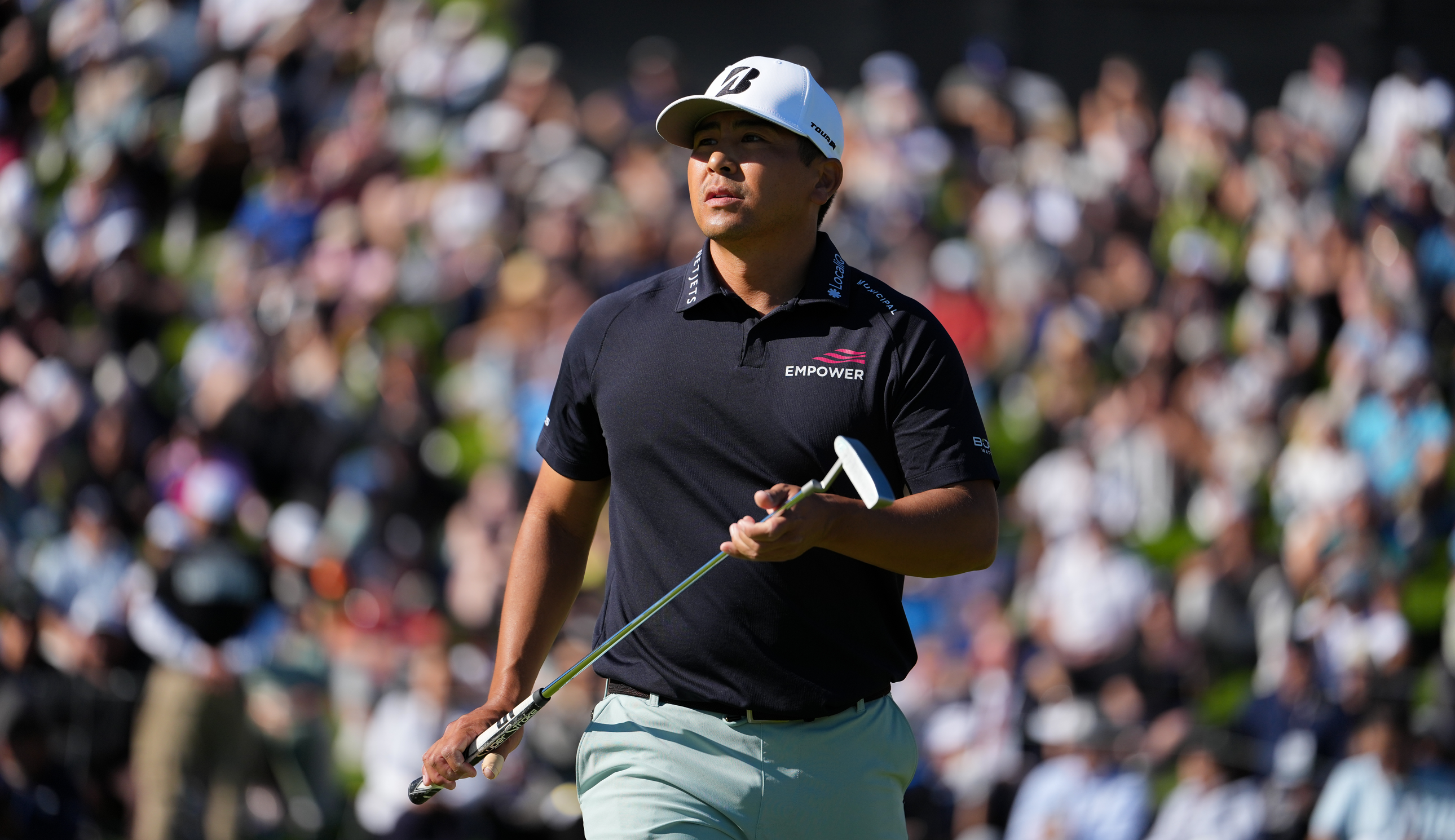 Kurt Kitayama walks off the green holding a putter