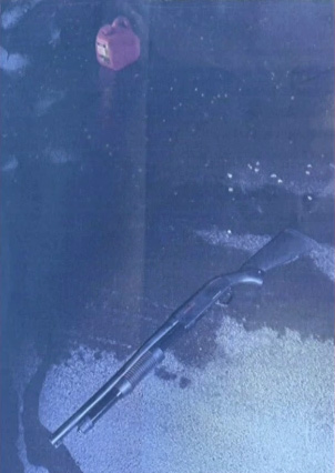 A black shotgun and a red gas can on a dark surface.