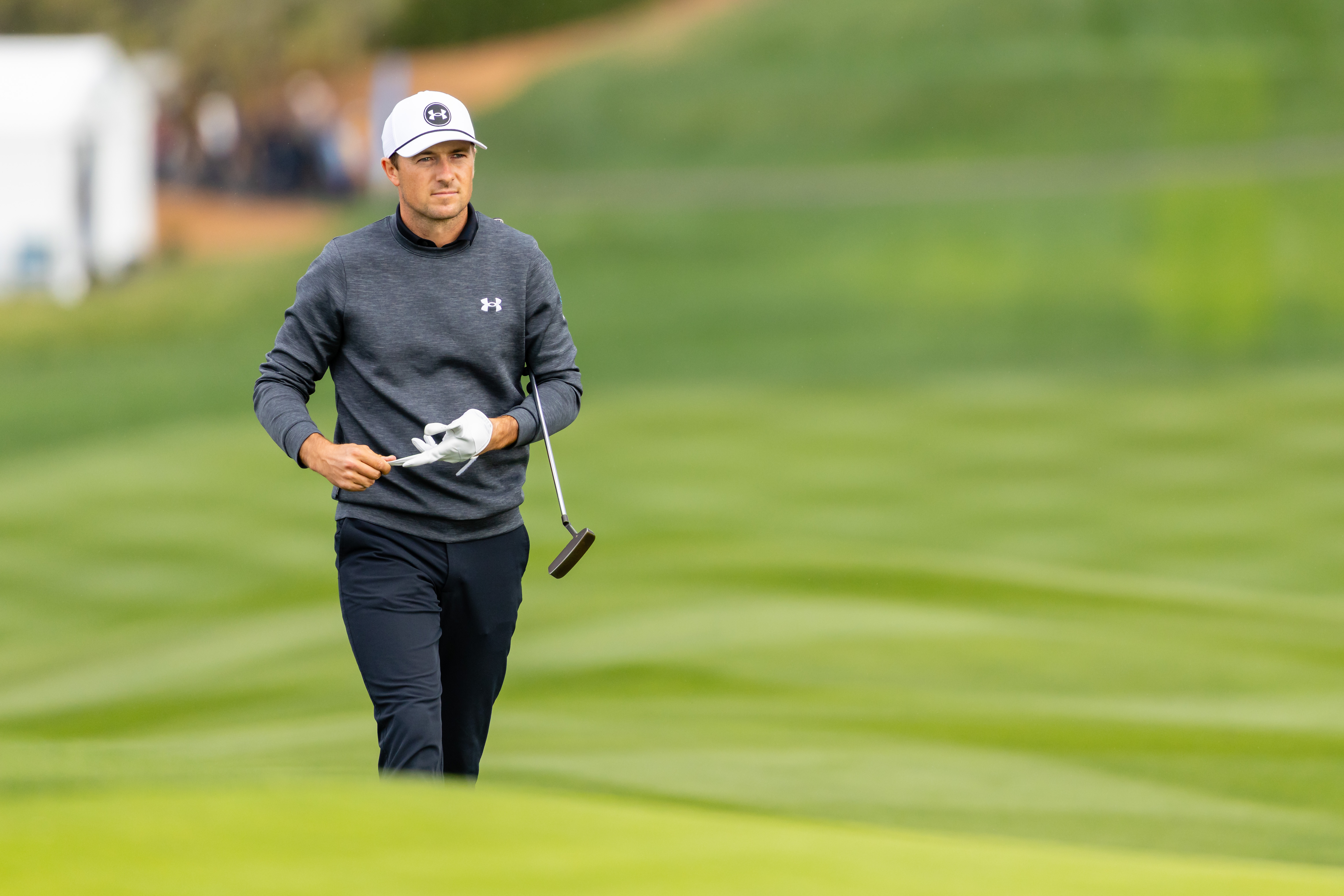 Jordan Spieth walks on the green holding a putter