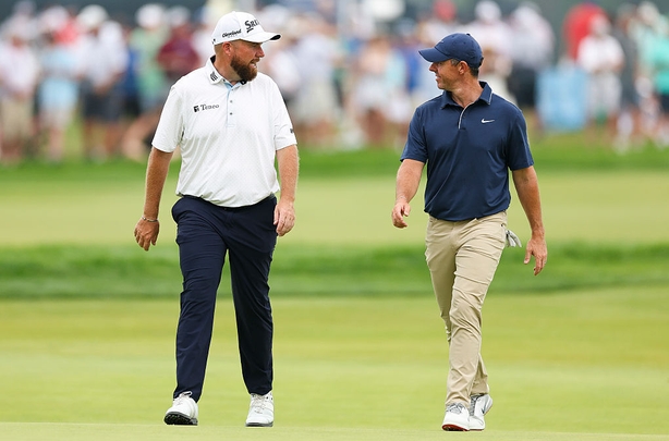 Shane Lowry talks with Rory McIlroy of Northern Ireland as they play golf together