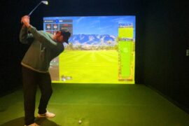 man swinging a golf club at a simulator