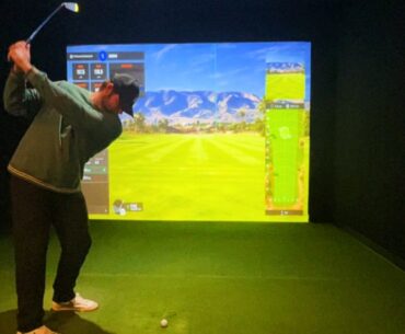 man swinging a golf club at a simulator