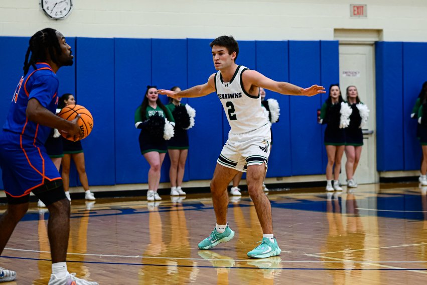 Jack McMullen on the court with his arms out, blocking a pass.