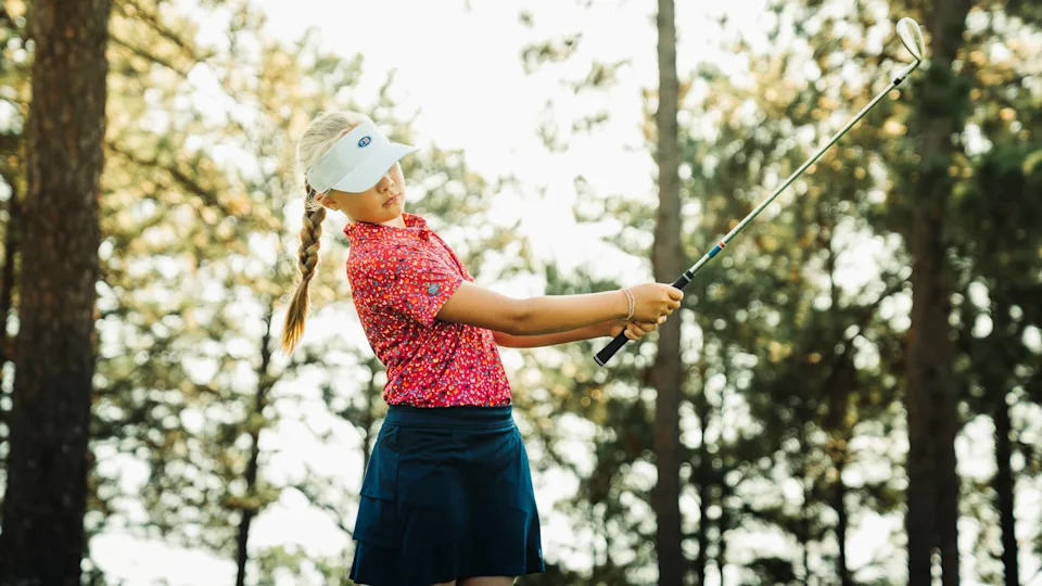 Junior female golfer swinging an iron