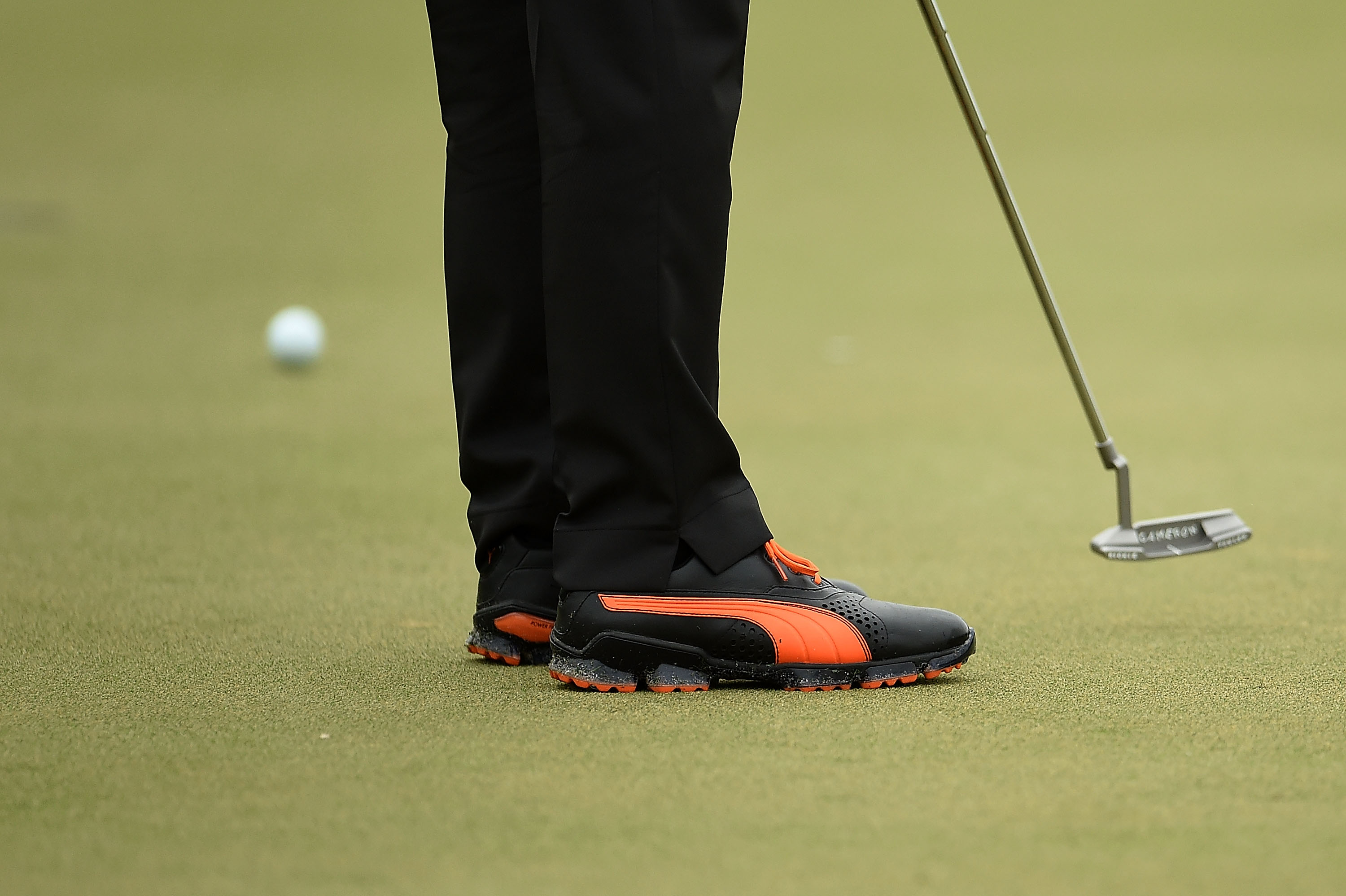 A close up of Rickie Fowler's shoes and putter