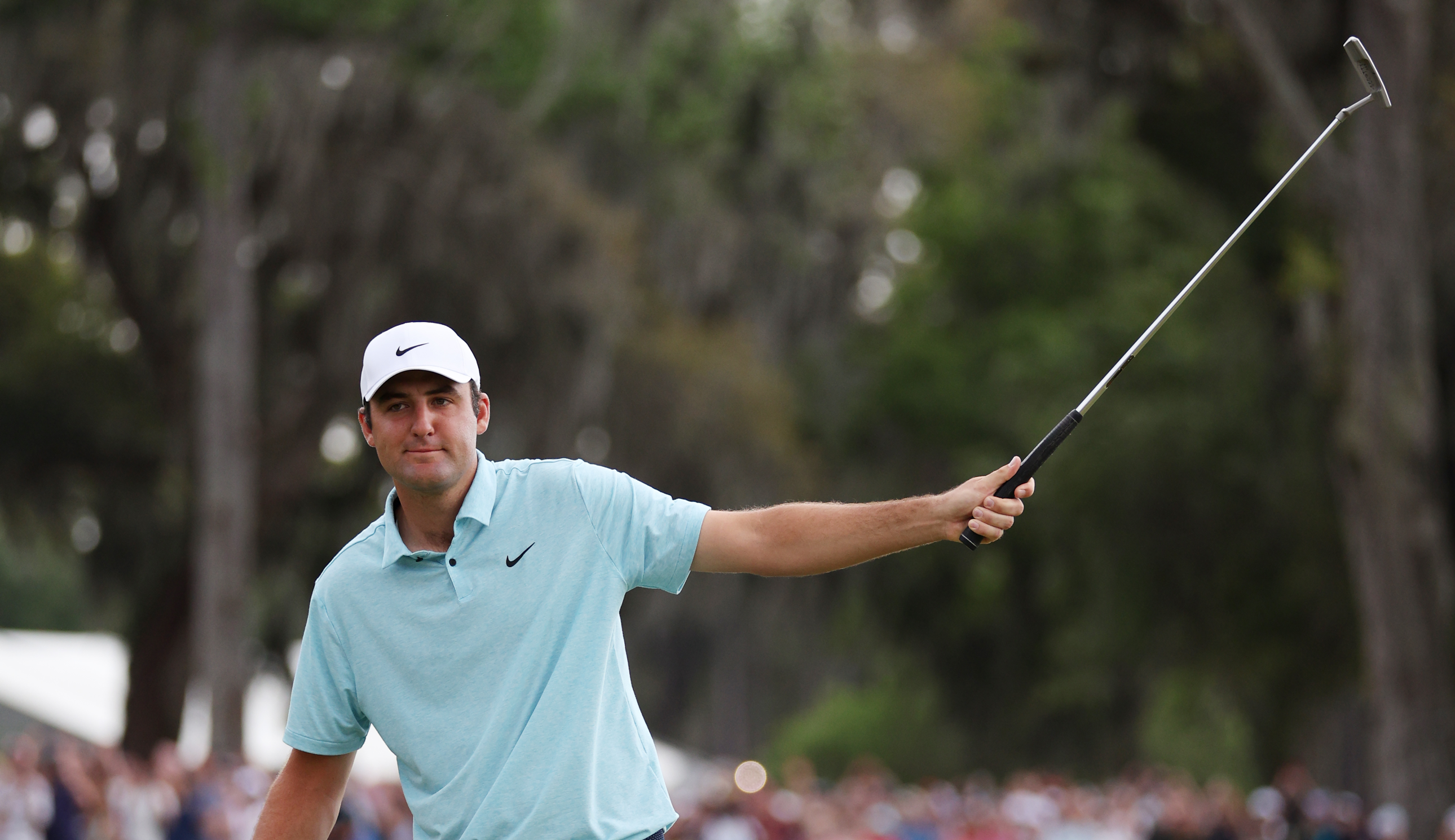 Scottie Scheffler raises his putter in the air