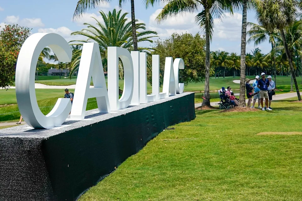 Fans watch from the shade near the 16th green during the first round of the Cadillac Championship golf tournament.