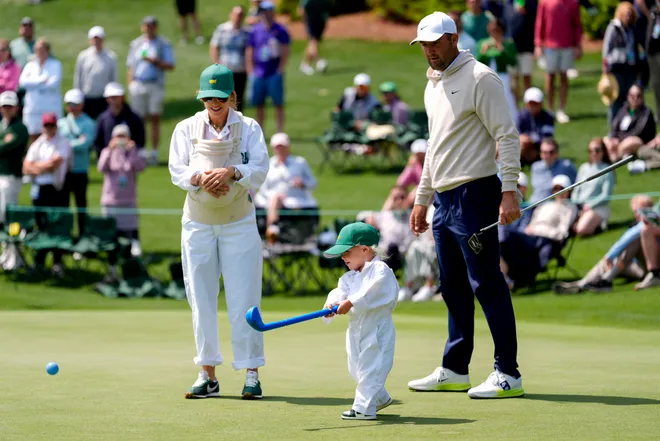 Scottie Scheffler and his wife, Meredith, watch as their son, Bennett, putts on the second green during the Par 3 Contest at the Masters Tournament at Augusta National Golf Club. With Meredith is their son Remy.