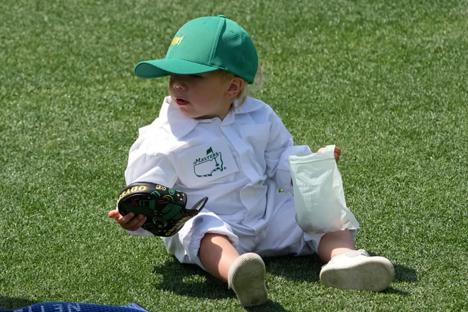 Bear, son of Sam Burns, sits on the fourth hole during the Par 3 Contest at the Masters Tournament at Augusta National Golf Club.
