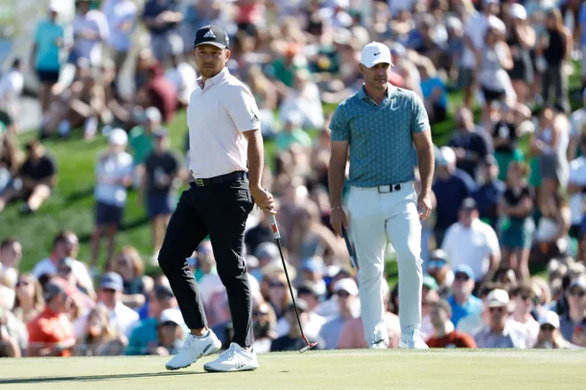 Brooks Koepka and Xander Schauffele of the United States stand on the second hole during the third round of the WM Phoenix Open at TPC Scottsdale on February 12, 2022 in Scottsdale, Arizona.