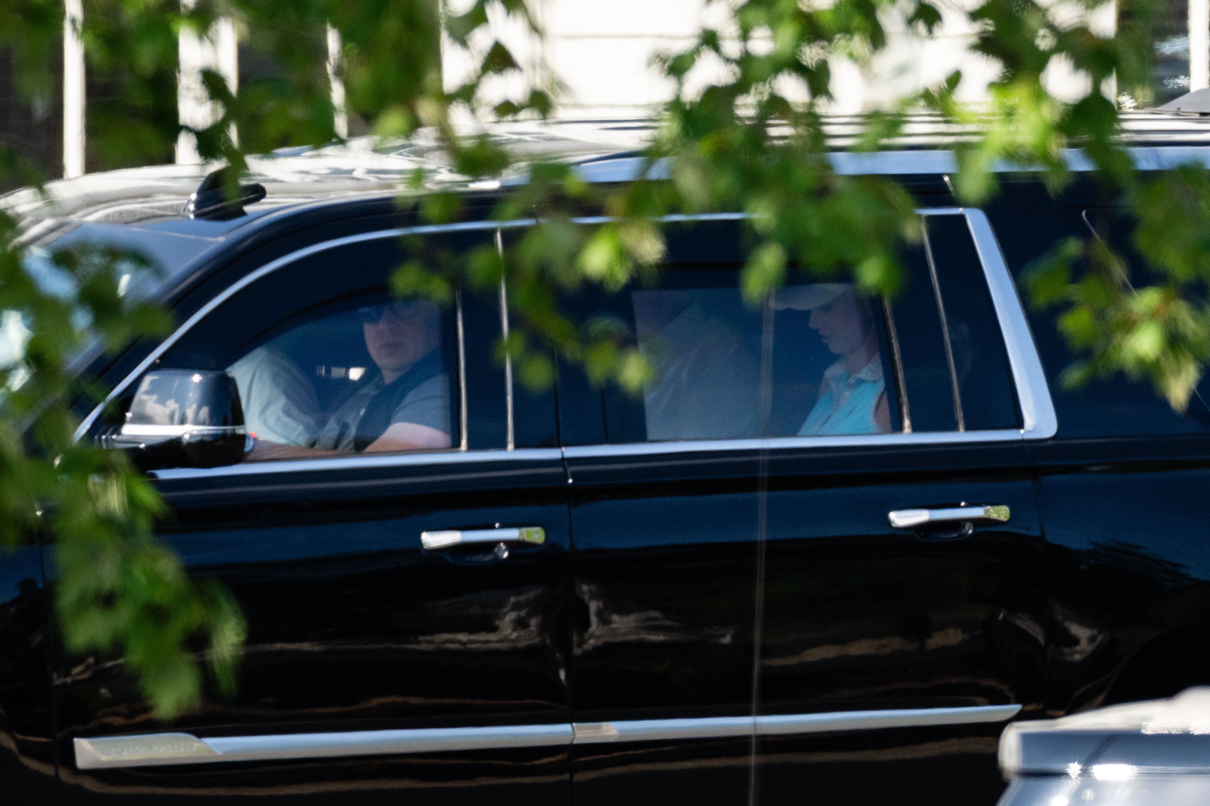 Harp rides in an SUV carrying Trump as they leave Trump National Golf Club