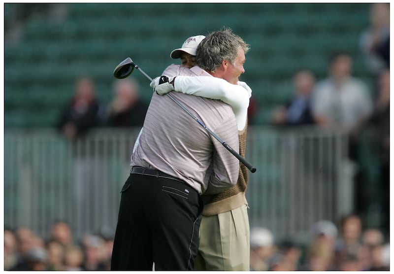 Darren Clarke receives a hug from Tiger Woods on the practice green. Photograph: Alan Betson